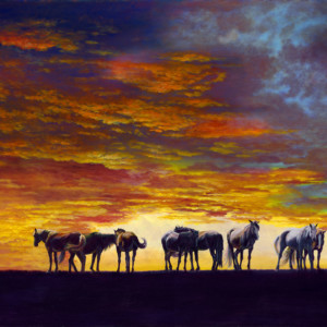 A herd of horses graze at sunset