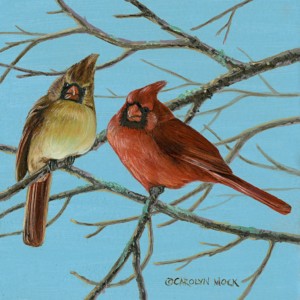 Two cardinals perched on a tree branch in the clear blue sky